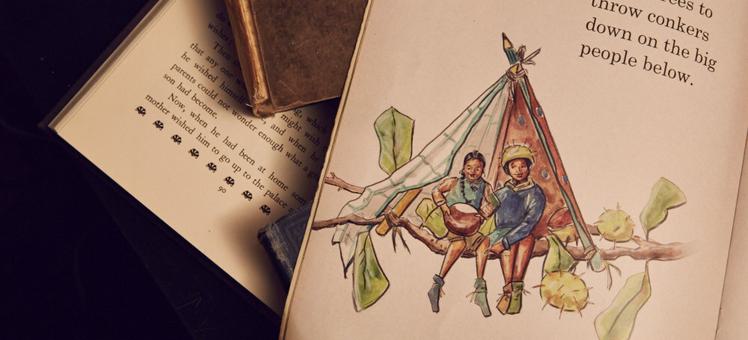 A photograph of an open storybook page. It has the text 'They built tiny tipis in tall trees to throw conkers down on the big people below'. You can see a drawing of two tiny people sat on a tree branch inside a tipi made with pencils and some cloth. Underneath is another open storybook and you can see text on the page.