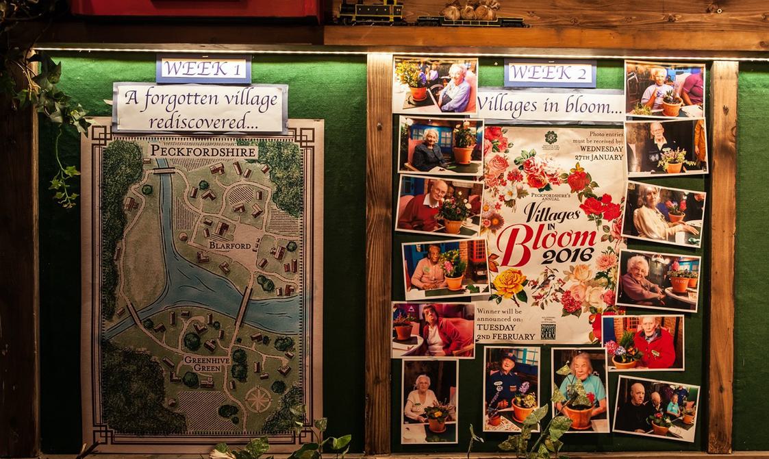 An image of a green darkly lit board with maps, photographs and text.