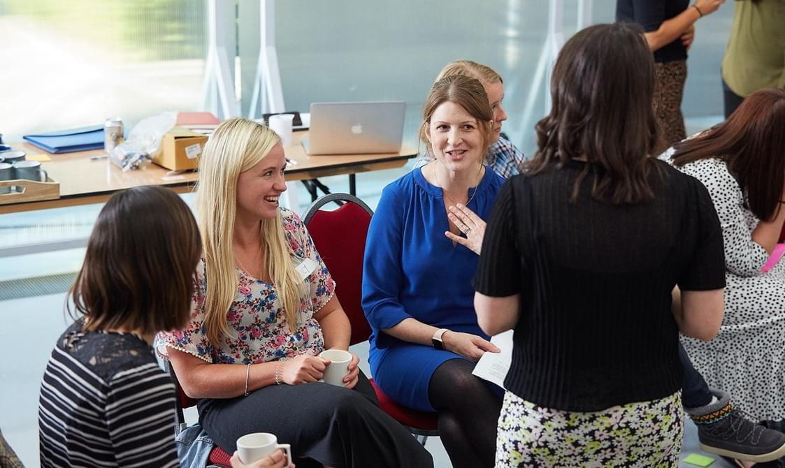 A group of teachers sit talking to each other.
