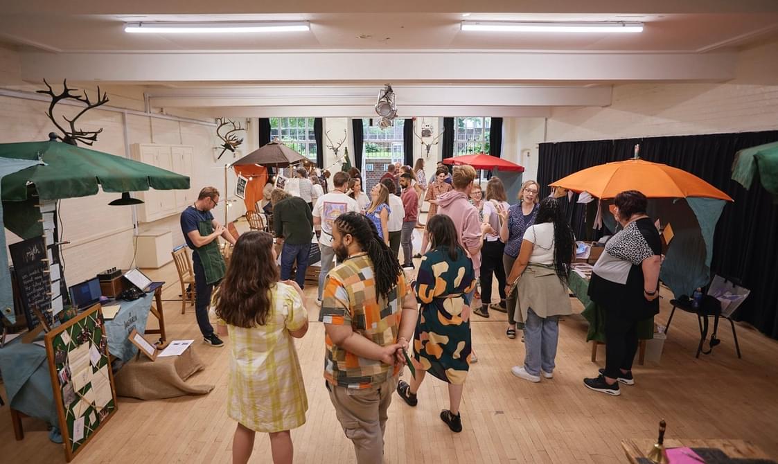A group of people standing in a room with colourful stalls.