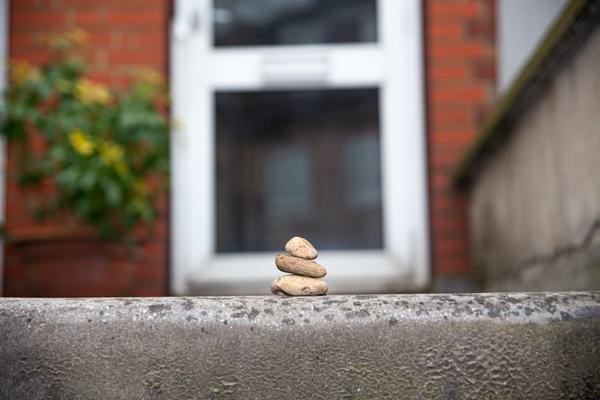 A collection of three stones stacked on top of each other in front of a red brick house.