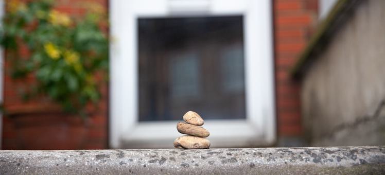 A collection of three stones stacked on top of each other in front of a red brick house.