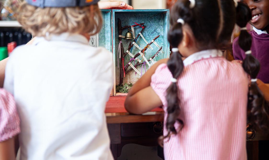 Two young children in school uniform look inside the wishing cupboard