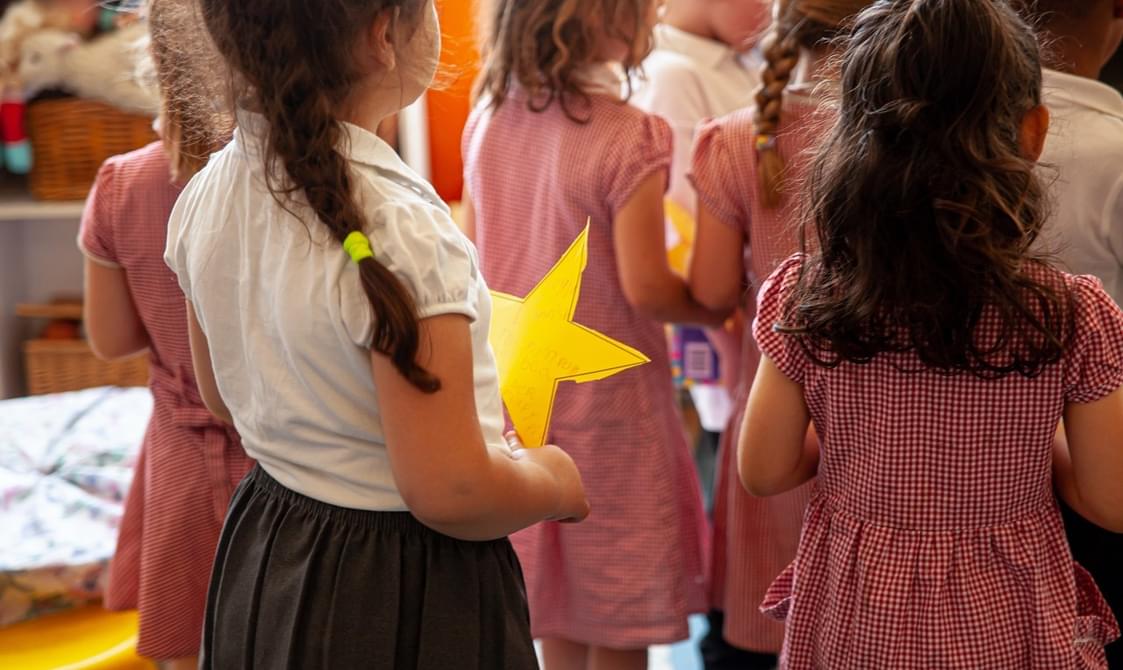 A group of young children in school uniform holding yellow stars